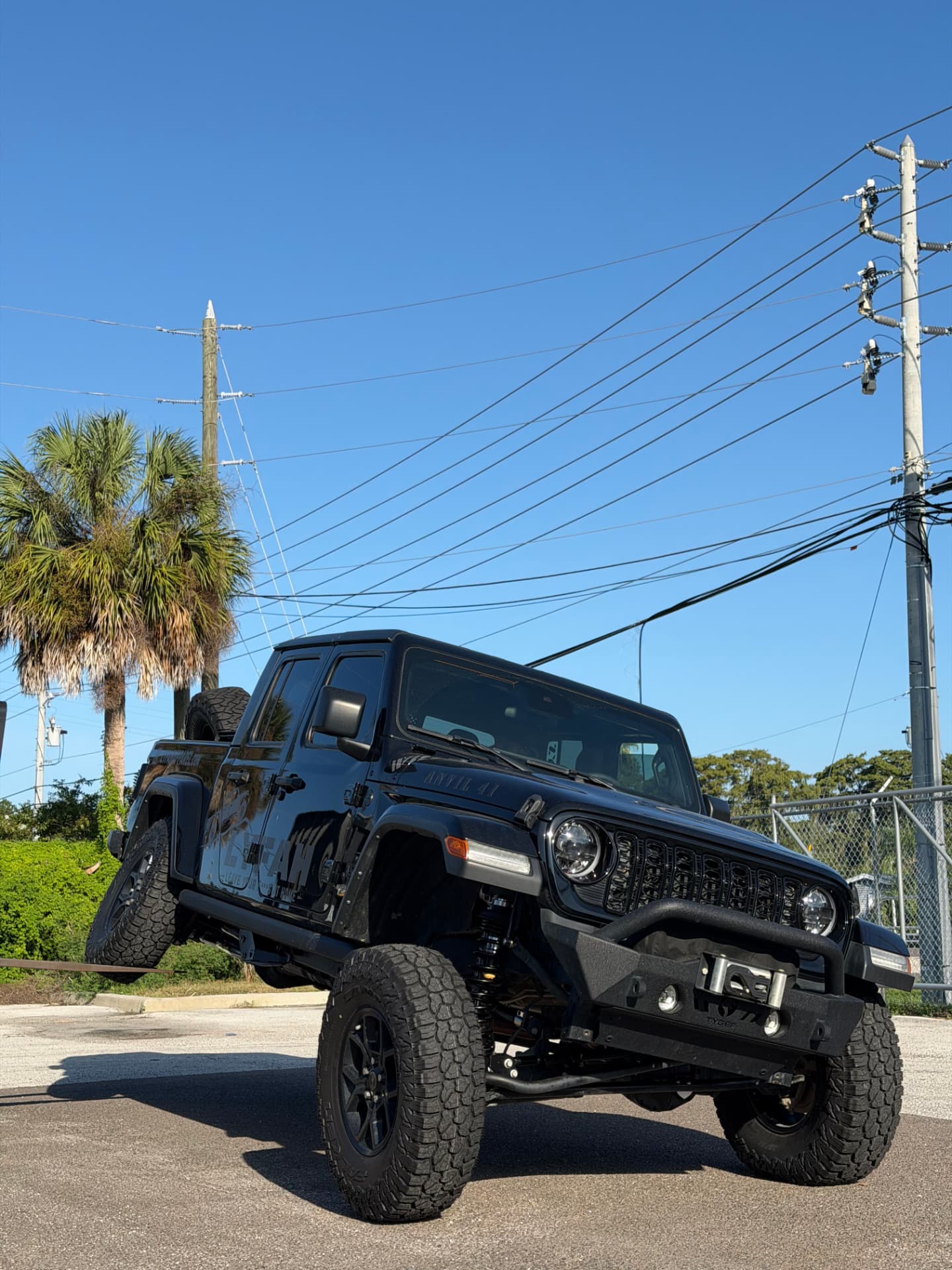 Gloss black 2024 Jeep Gladiator Sport 'Anvil 41' with TeraFlex CT3 suspension and 37-inch Toyo ATIII tires on 17-inch Dirty Life DT-1 bead locks, articulating on a flex ramp at SunCoast Off-Road in New Port Richey, FL