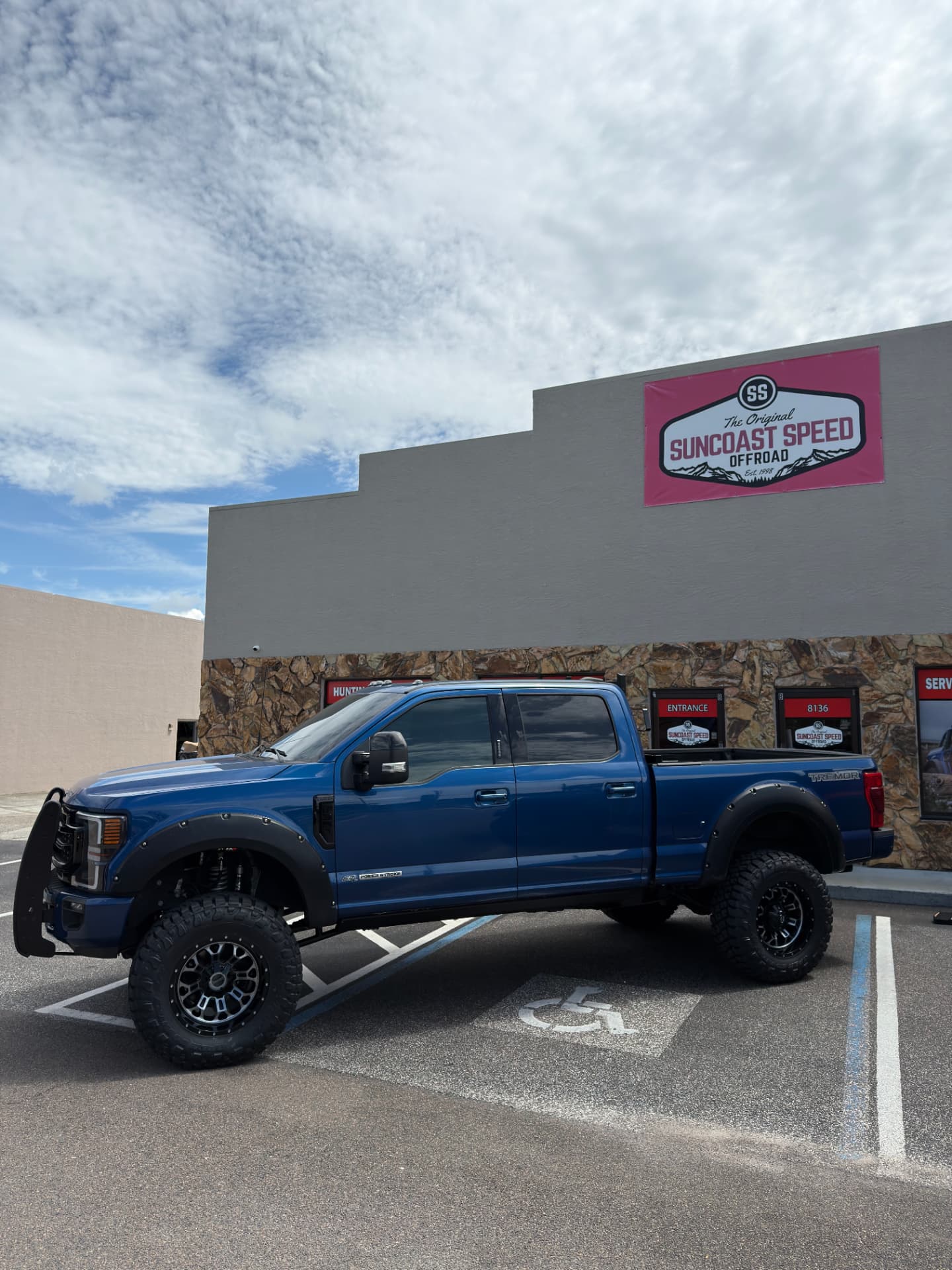 Blue 2022 Ford F-350 Tremor with 7-inch BDS coilover conversion and FOX 2.5 Performance Elite coilovers, 38-inch Toyo R/T Pro tires on 20-inch Fuel wheels, headache rack and RIGID lighting, at SunCoast Off-Road in New Port Richey, FL